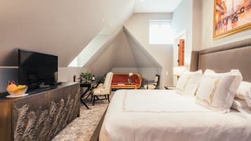 Une chambre d’hôtel avec un grand lit, un téléviseur posé sur un meuble, un bureau avec une chaise et un tableau accroché au mur.