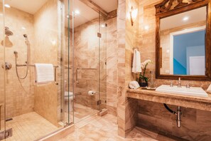 A modern bathroom with a glass-enclosed shower, a vanity with a sink, and a large mirror. - Sutter Mansion (San Francisco)
