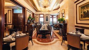 A formal dining room with a long table, chairs, and a chandelier.