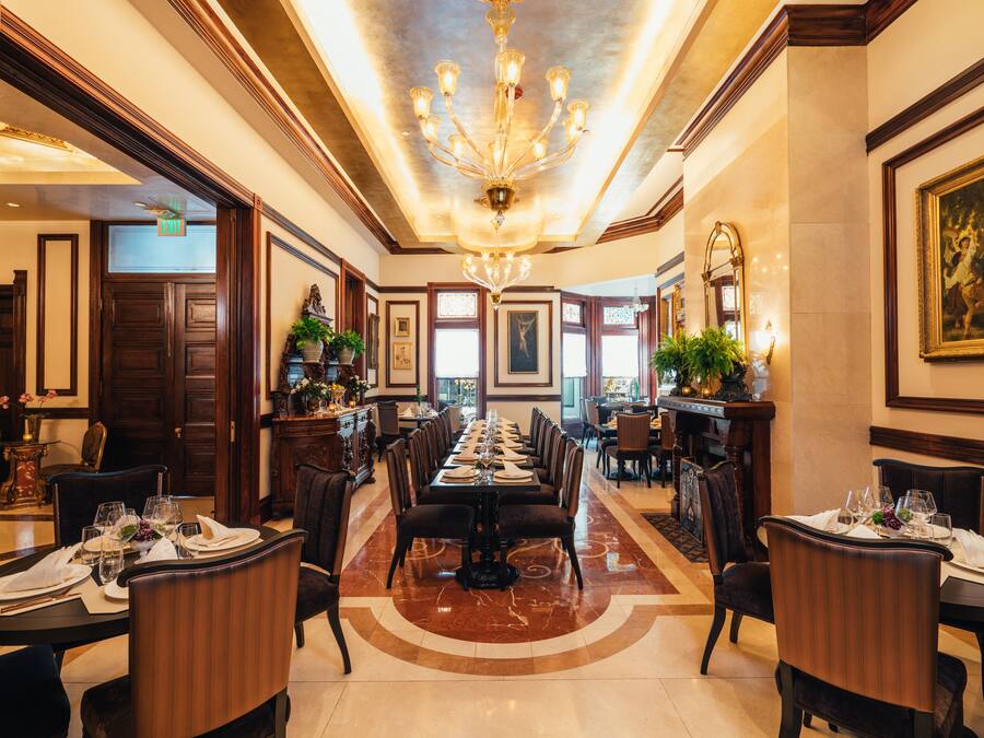 A formal dining room with a long table, chairs, and a chandelier.