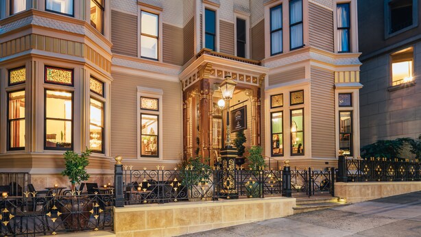 A historic building with ornate architectural details, large windows, and a well-lit entrance.