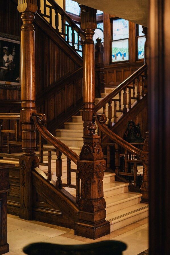 A grand wooden staircase with intricate balusters and a polished marble floor. - Sutter Mansion (San Francisco)