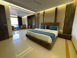 A modern bedroom with a large bed, a ceiling fan, and a view of the adjacent living area. - Hotel Gyan (Haridwar)