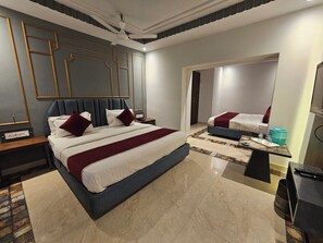 Une chambre d’hôtel avec un grand lit, un lit plus petit, un bureau avec un ordinateur et un distributeur d’eau.