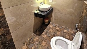 A modern bathroom with a toilet, sink, and towel rack. - Hotel Gyan (Haridwar)