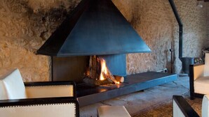 A stone-walled room with a large, modern fireplace, a sofa, and a small table.