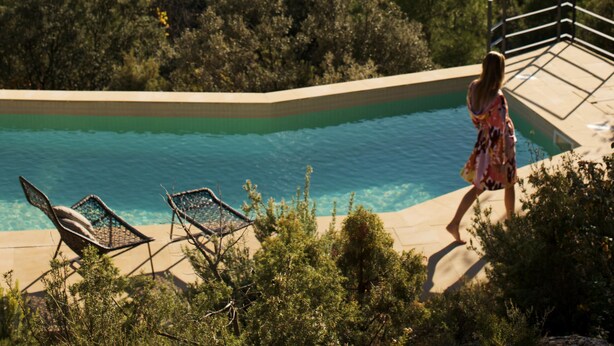 A pool with a view of a forested hillside.