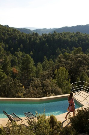 A pool with a view of a forested hillside.