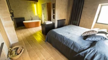 Un dormitorio moderno con una cama grande, una bañera y piso de madera.