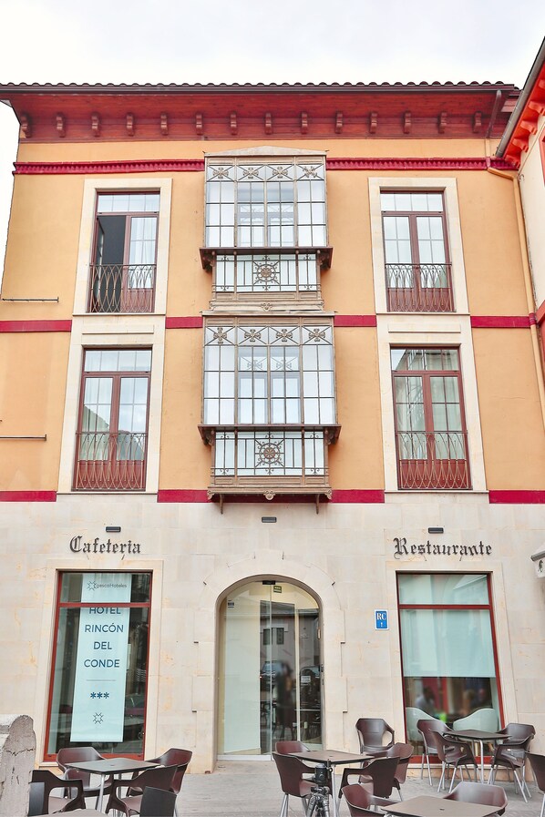 A hotel facade with a sign for 'Hotel Rincón del Conde' and 'Restaurante'. There are outdoor tables and chairs in front. - Rincón Del Conde (León)