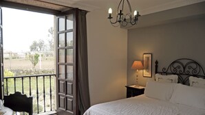 Un dormitorio con una cama grande, una mesita de noche, una lámpara y vistas al exterior a través de un ventanal.