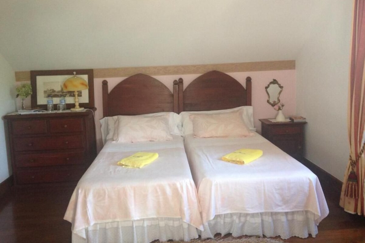 A double bed with two pillows and a bedside table with a lamp.