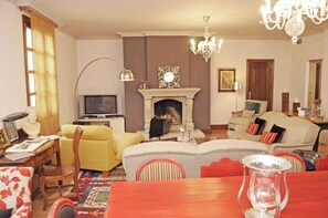 A living room with a fireplace, sofa, television, and a dining table.
