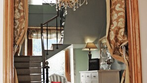 Una escalera conduce a un rellano con una araña, una silla y un armario.