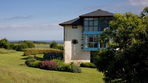 A single-story building with a sloped roof, surrounded by a well-maintained garden with various shrubs and a lawn. - Rusticae Hotel Torre de Villademoros (Valdes)