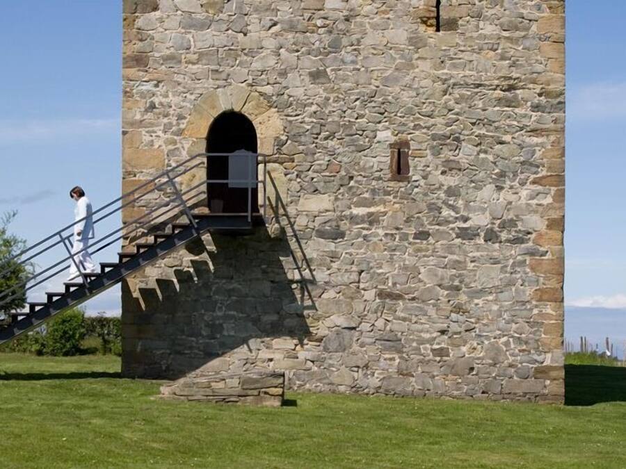 Una torre de piedra con una escalera que conduce a un ventanal en arco.