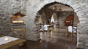 Een restaurant met stenen muren, houten tafels en stoelen.