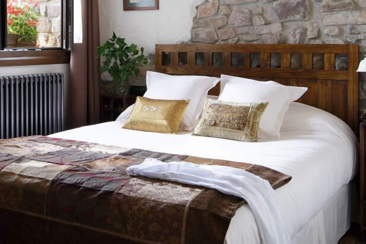 Un lit bien fait, avec une couvre-lit à motifs, une tête de lit en bois et des coussins décoratifs.