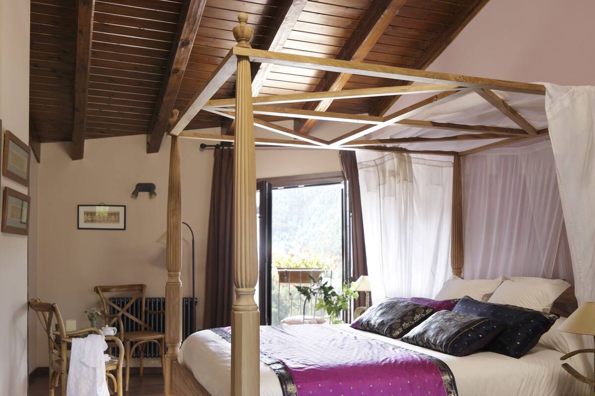 Un lit à baldaquin, un tapis rond et une chaise en bois.
