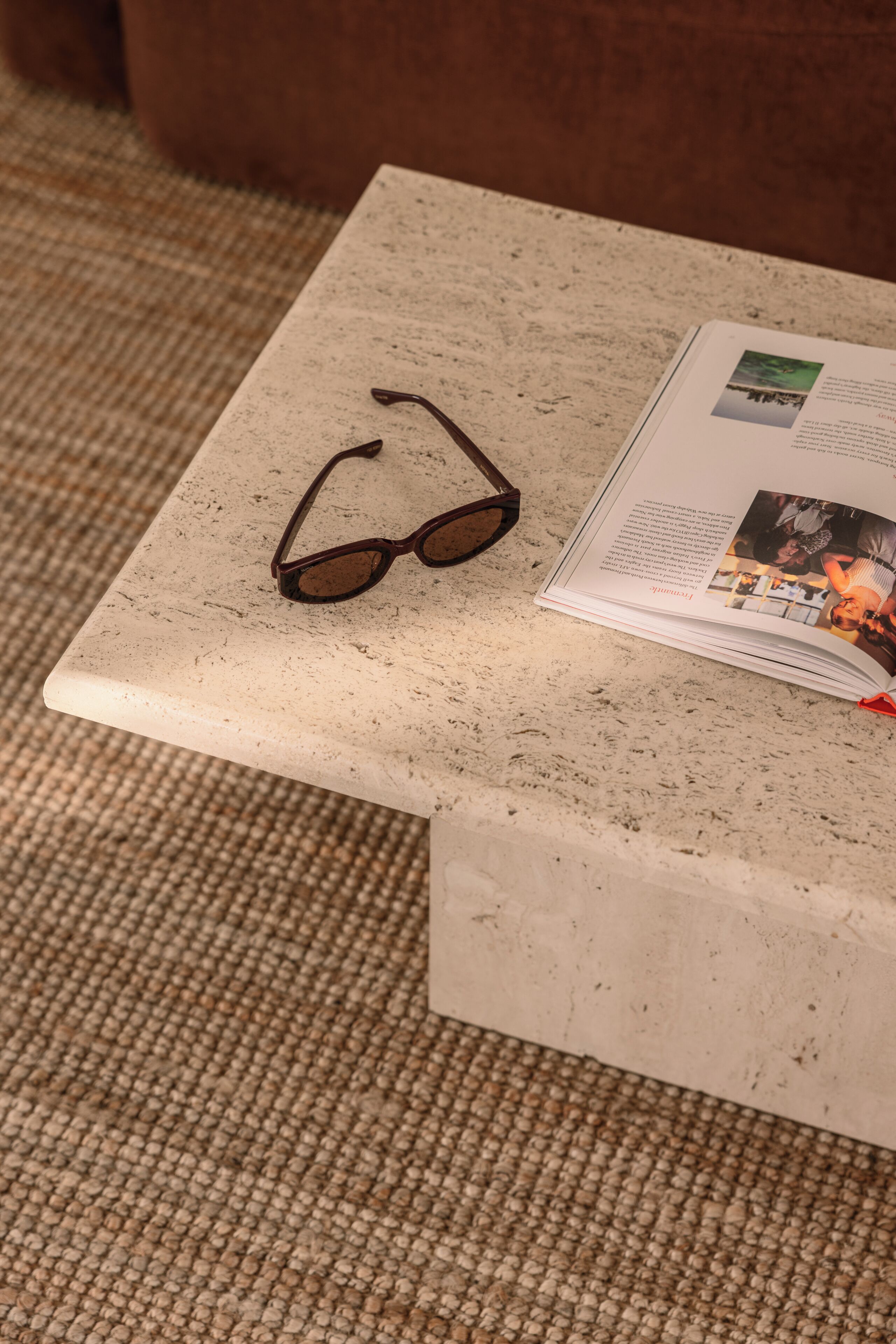 A pair of glasses on a marble table with a magazine.