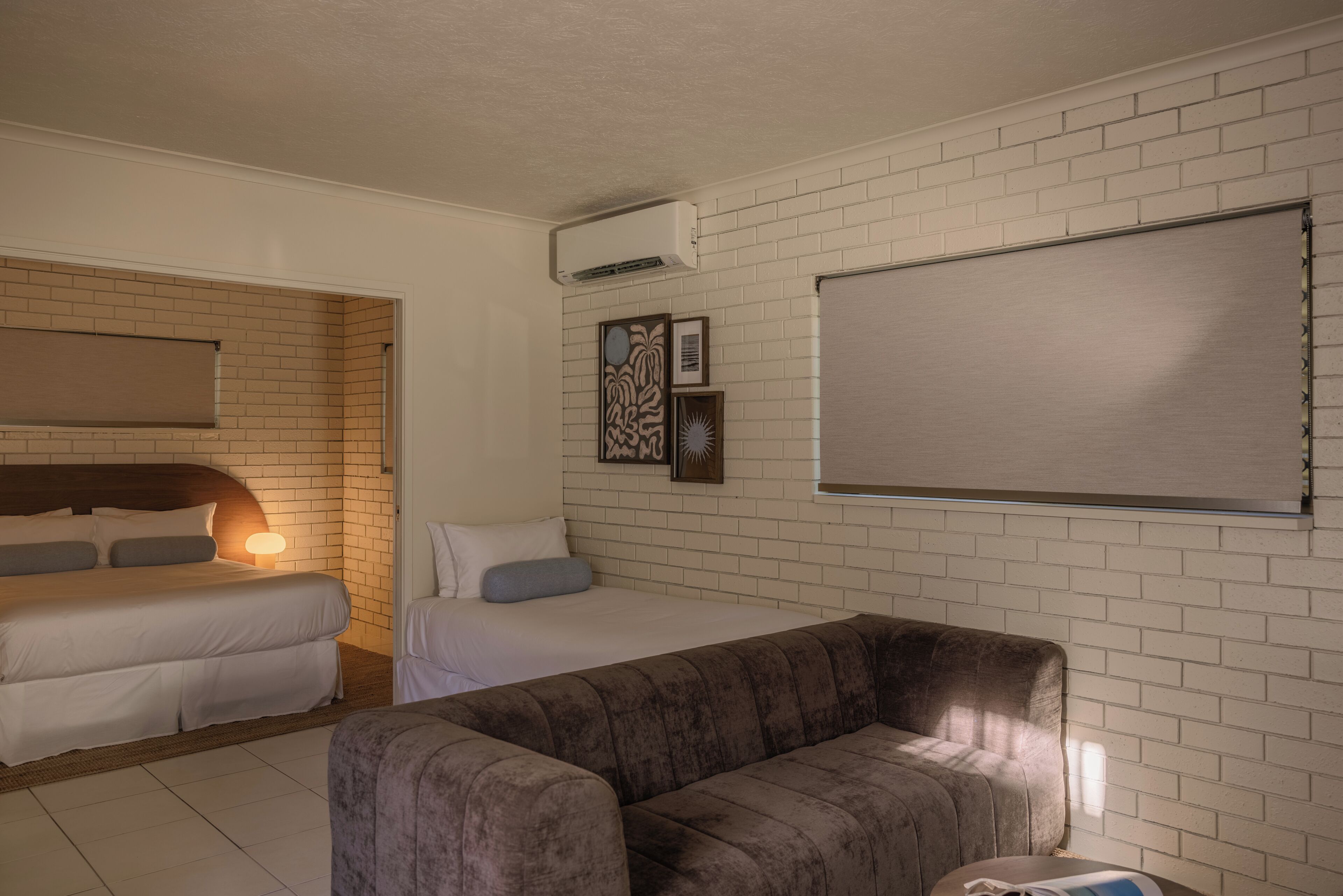 A room with a bed, a sofa, a wall-mounted air conditioner, and a large blank board.