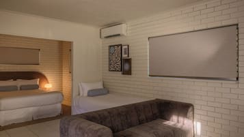 A room with a bed, a sofa, a wall-mounted air conditioner, and a large blank board.