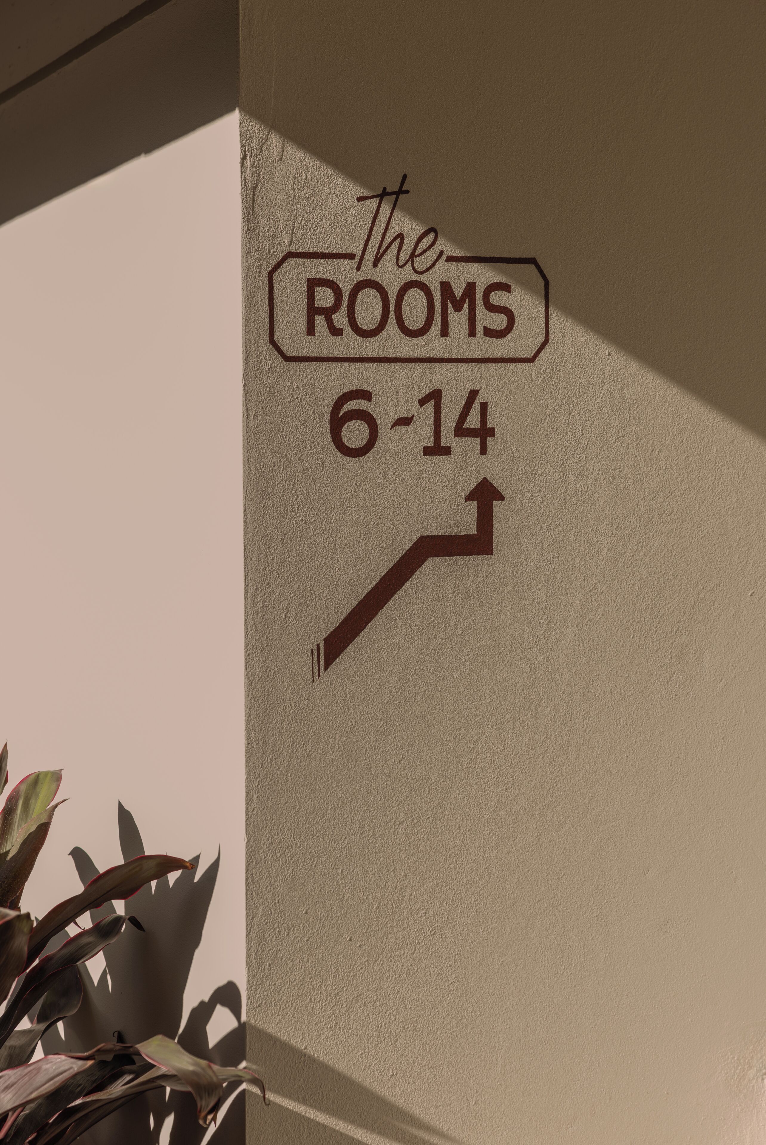 Placa na parede indicando 'The Rooms 6-14' com uma seta apontando para cima.