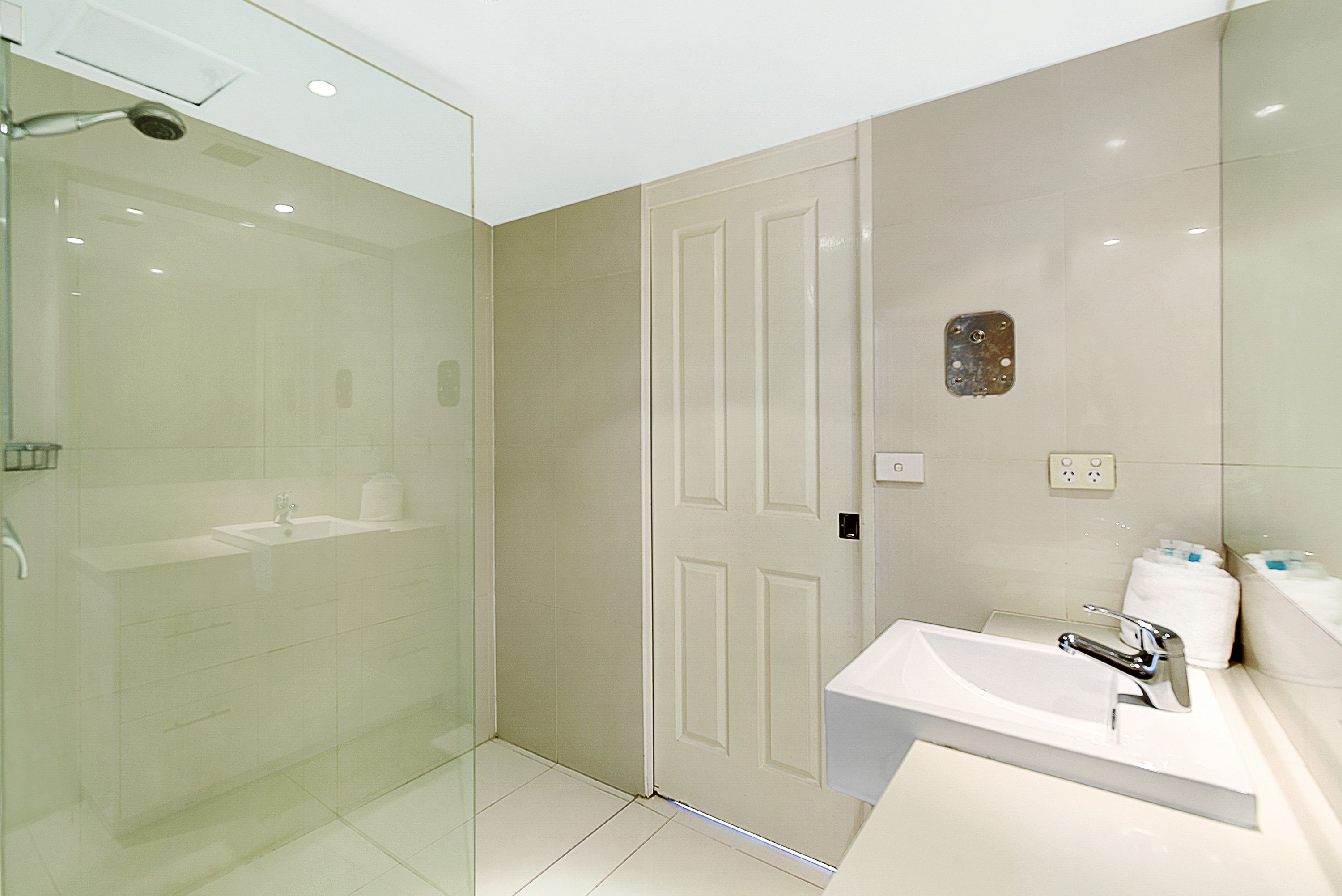 A modern bathroom with a glass-enclosed shower, a white sink, and a mirror.