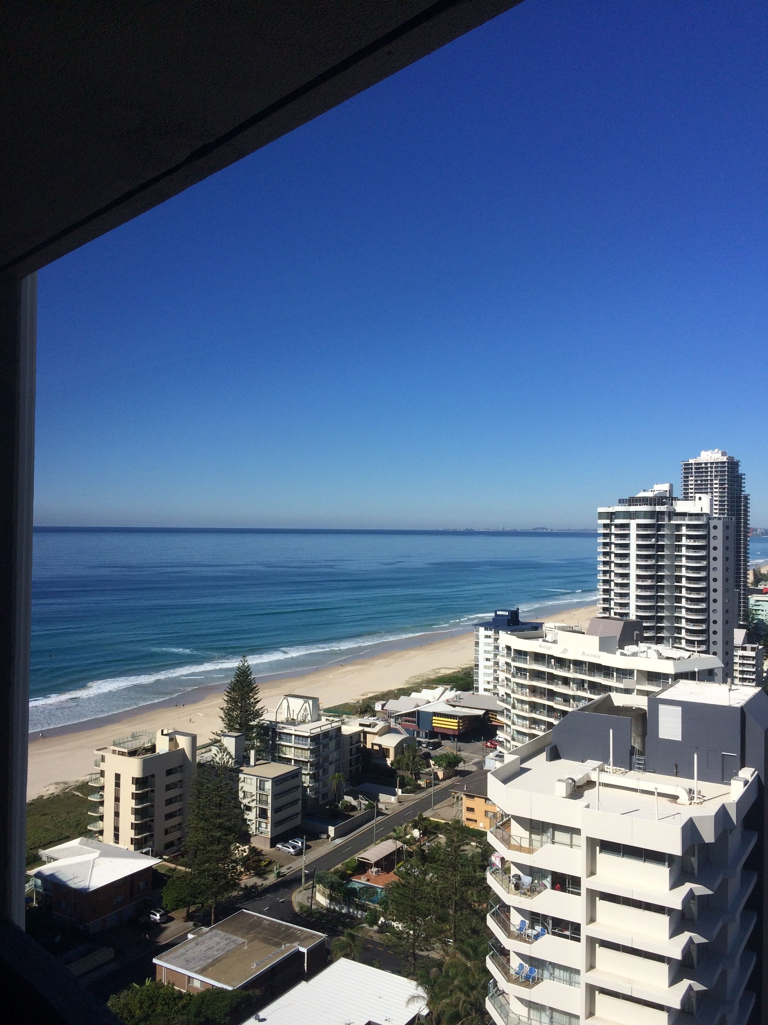 Un paysage urbain côtier avec une plage, des immeubles de grande hauteur et un ciel bleu dégagé.
