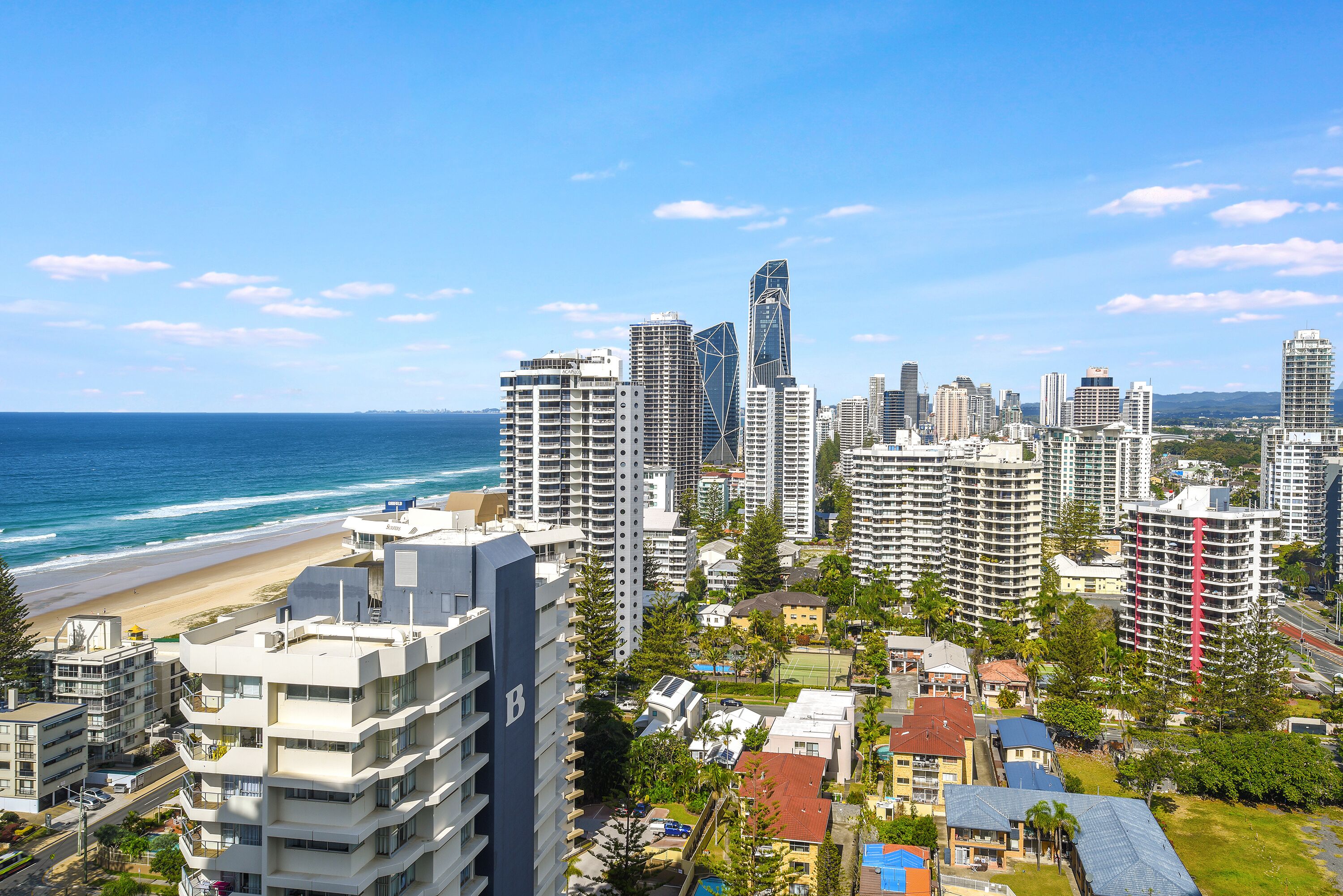 A coastal cityscape with high-rise buildings, a beach, and a clear sky.