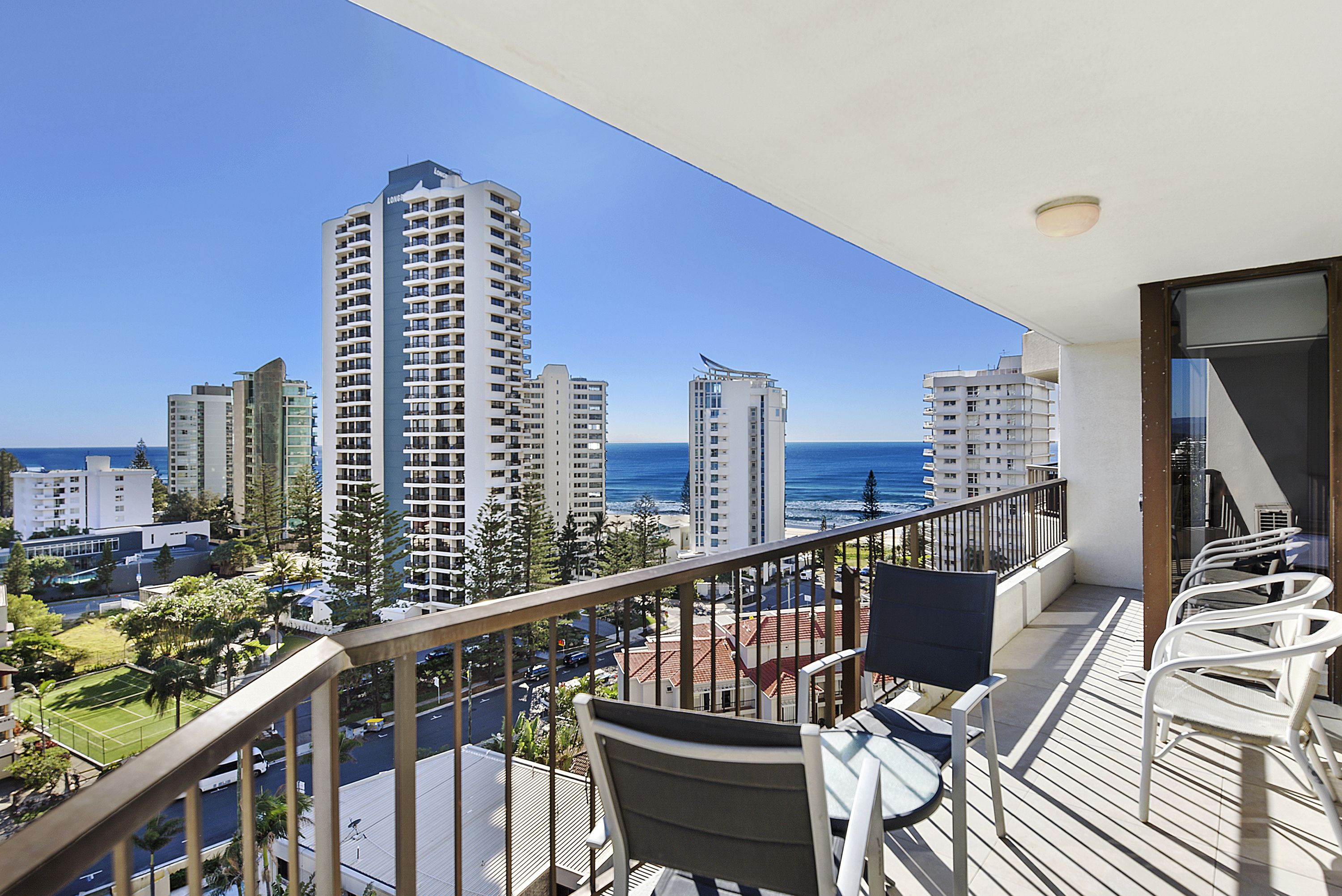 A balcony with a view of the ocean and surrounding high-rise buildings.