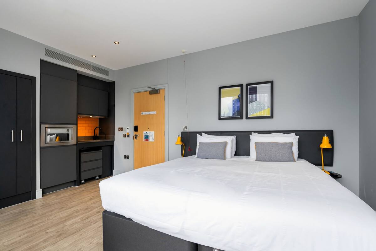 Une chambre d’hôtel moderne dotée d’un grand lit, d’un bureau intégré et d’un four à micro-ondes.