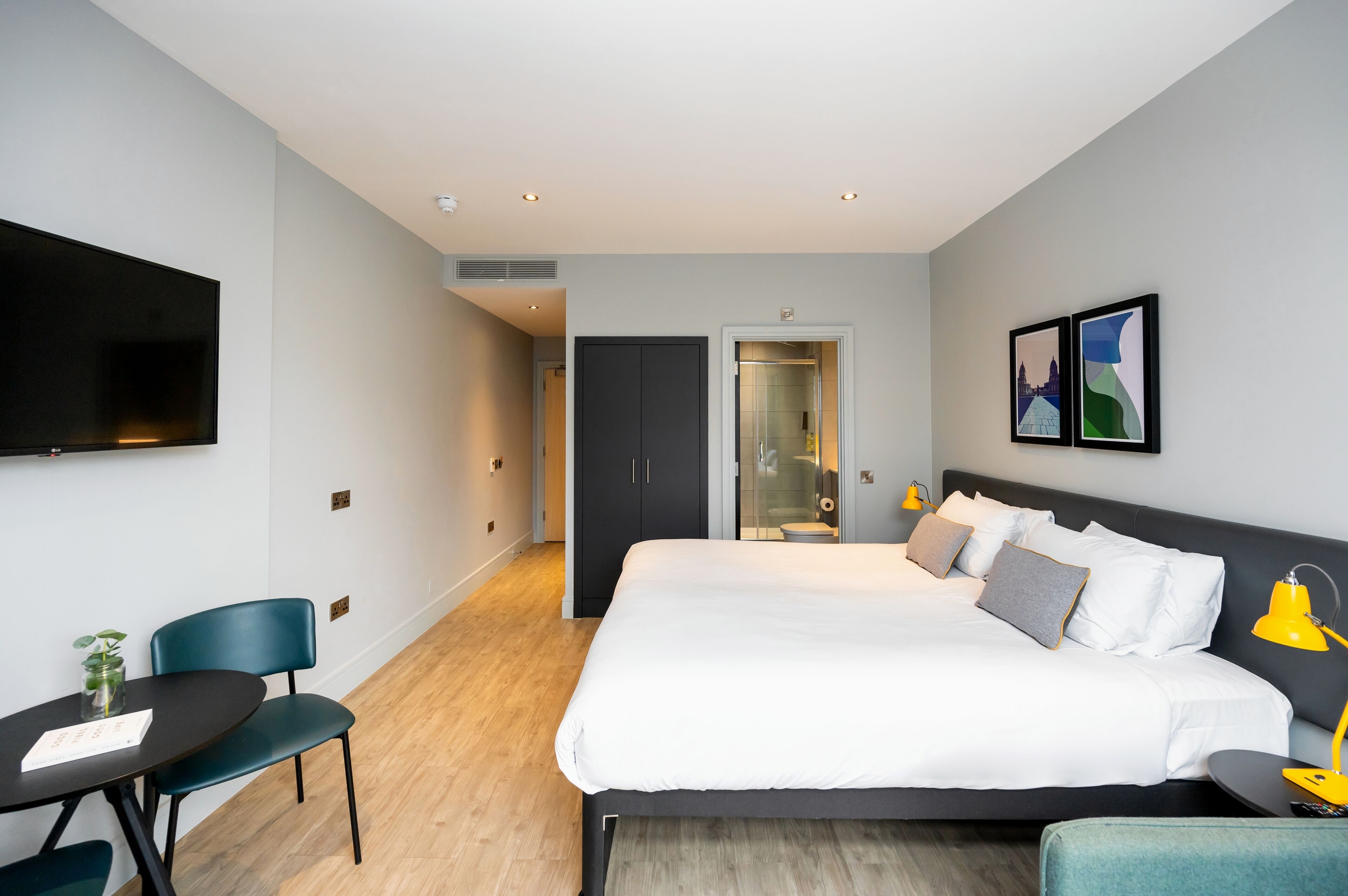 Una habitación de hotel moderna con una cama grande, un escritorio y un televisor.
