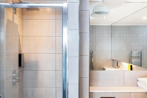 Ein modernes Badezimmer mit Duschkabine aus Glas, einem großen Spiegel und einem integrierten Handtuchhalter.