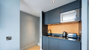 Een moderne keuken met grijze kastjes, een magnetron, een waterkoker en een broodrooster.