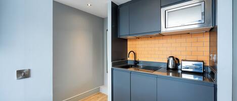 A modern kitchen with grey cabinets, a microwave, a kettle, and a toaster.