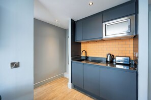 Una cocina moderna con armarios grises, un microondas, una tetera y un tostador.