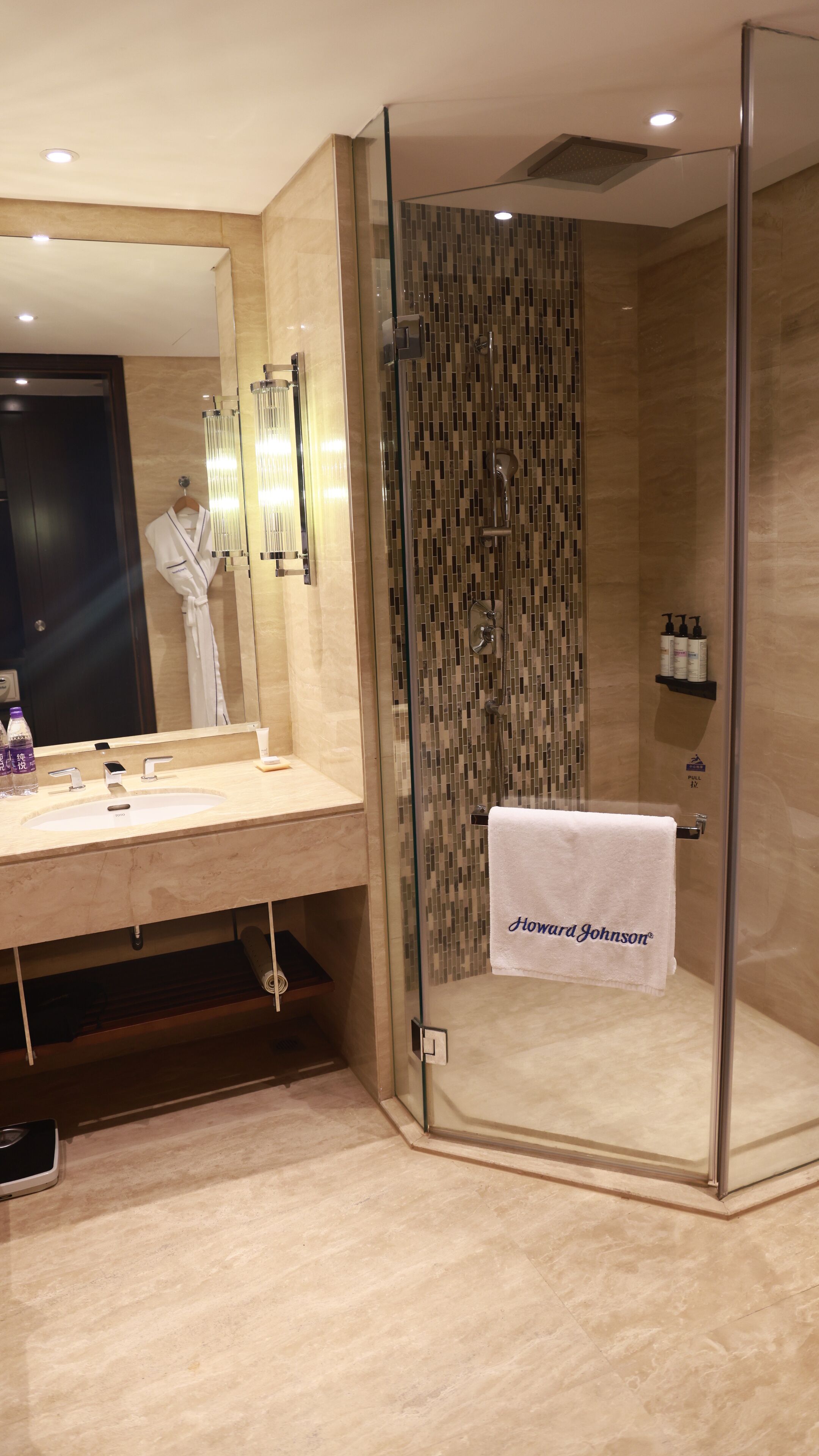 A modern bathroom with a glass-enclosed shower, a vanity with a mirror, and a towel rack with a towel.