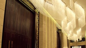 Un hall d’entrée spacieux, doté d’un sol en marbre poli, de grandes portes en bois foncé et de lustres modernes.