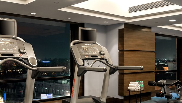 A modern gym with treadmills, a stationary bike, and a weight bench. - Hyatt Raipur (Raipur)