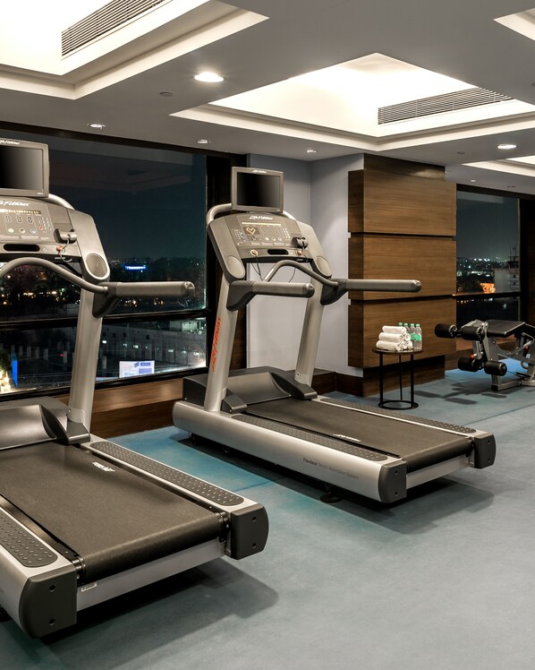 Un gimnasio moderno con cintas de correr, una bicicleta estática y un banco para pesas.