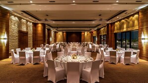 A large banquet hall with round tables, white chairs, and a patterned carpet. - Hyatt Raipur (Raipur)