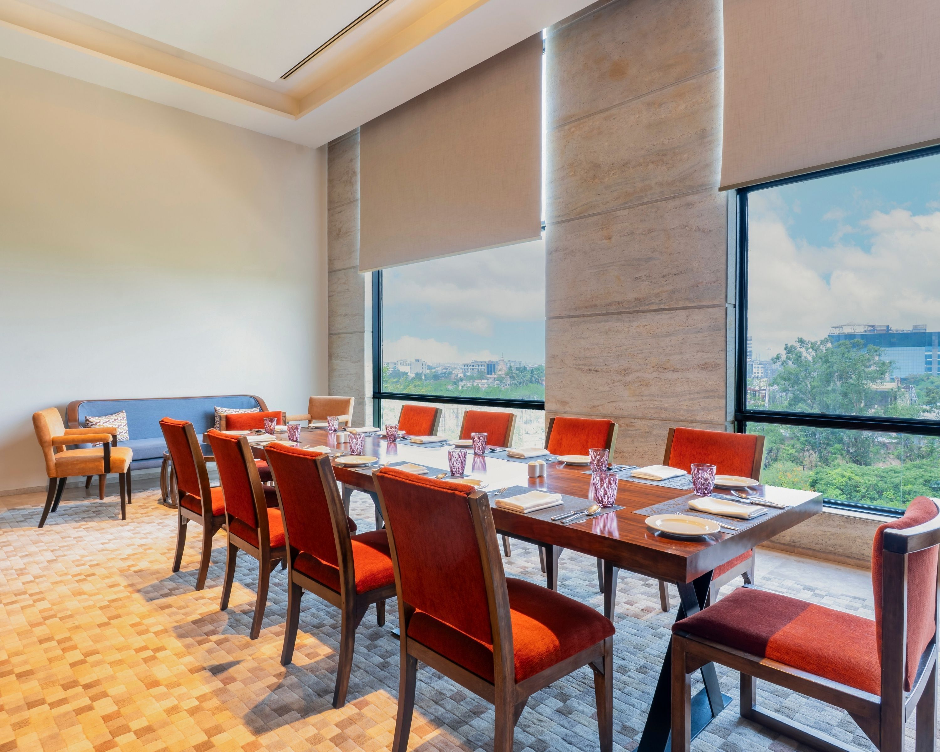 Un salón de conferencias con una mesa grande, sillas y vistas a la ciudad a través de amplios ventanales.