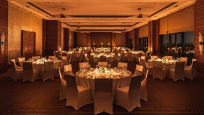 A banquet hall with round tables set for dining, featuring a central floral arrangement and candles. - Hyatt Raipur (Raipur)