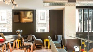 Un intérieur moderne avec une longue table, plusieurs chaises, un téléviseur et de grandes fenêtres.