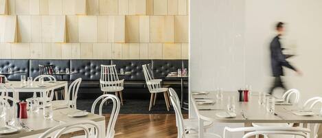 Un interior de restaurante moderno con mobiliario blanco, un banco acolchado negro y suelo de madera.