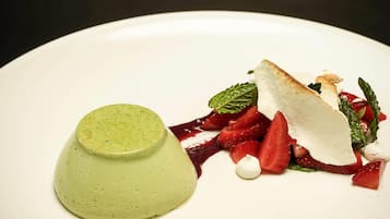 Un dessert avec une portion en forme de dôme vert et une tranche blanche, le tout présenté sur une assiette blanche.