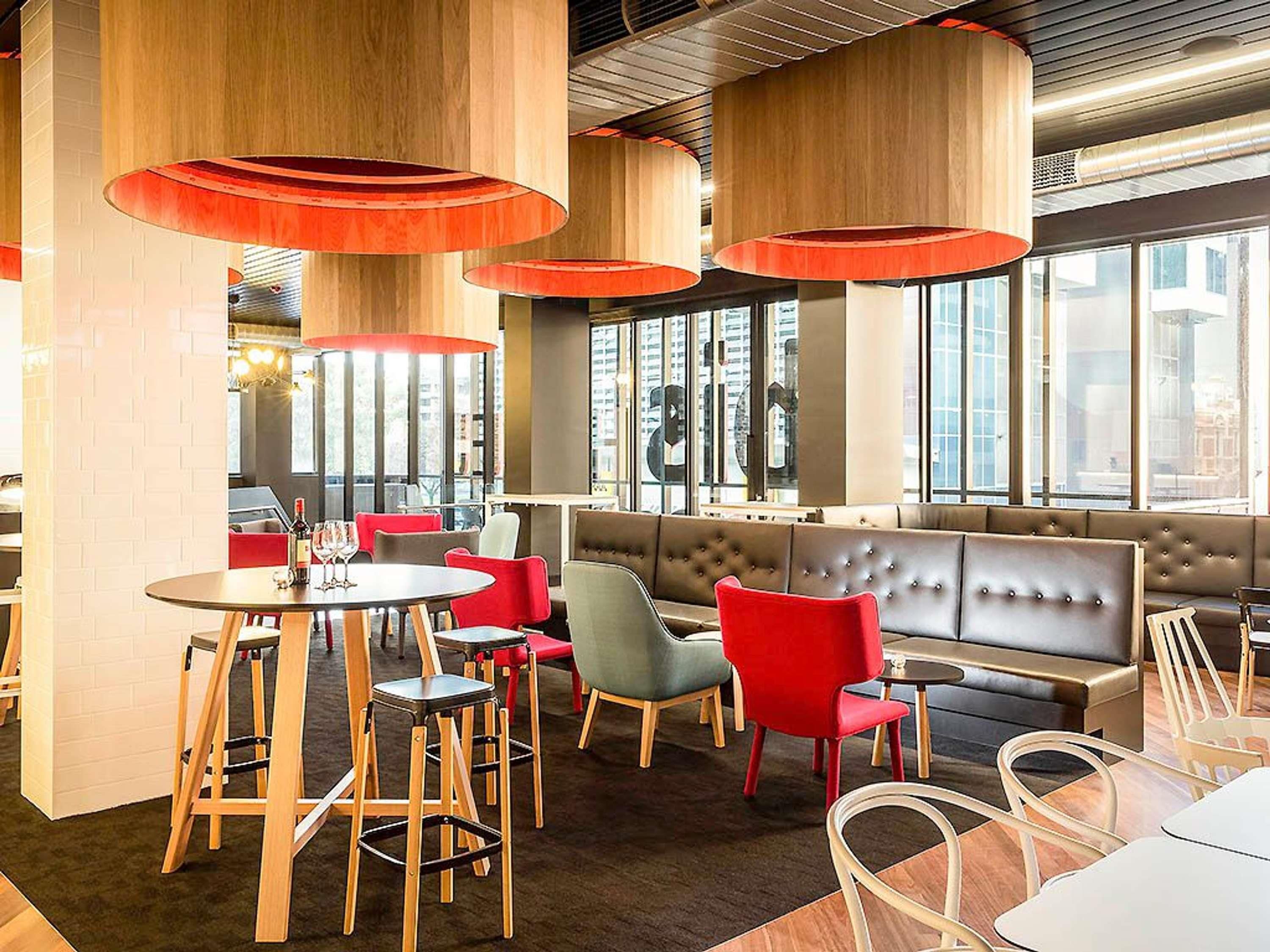 A modern interior with round tables, red chairs, and a large cushioned seating area.