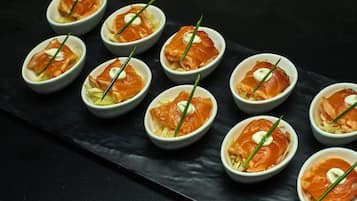 A series of small bowls containing a dish with smoked salmon and cream, garnished with chives, arranged on a dark slate serving board.