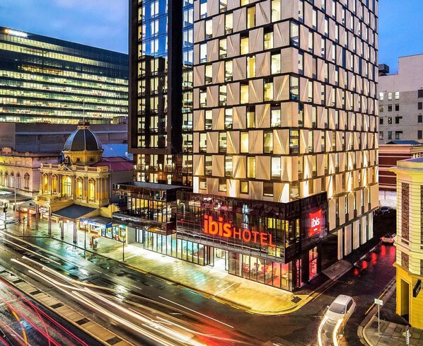 A modern hotel with a glass facade, located at a city intersection. - ibis Adelaide (Adelaide)